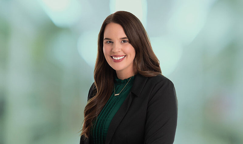Emily McVey smiling in black suit with green blouse