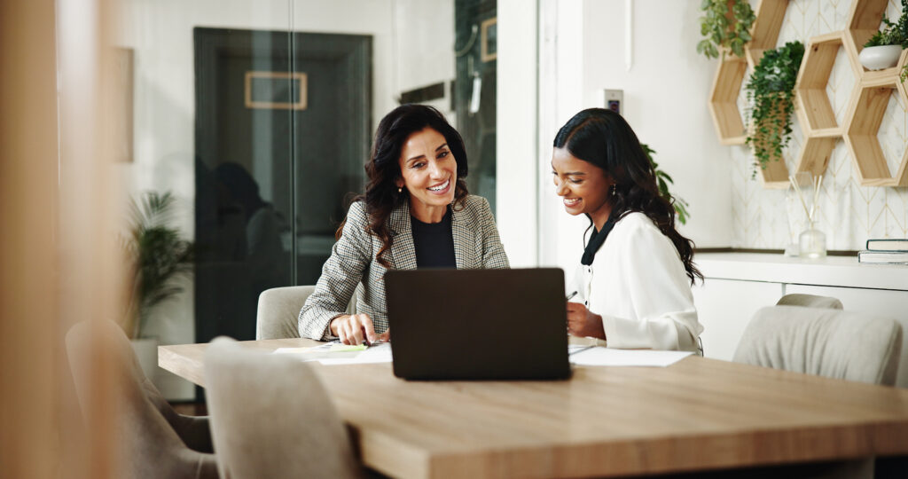 Two women looking at papers and a computer in a meeting room at a bank