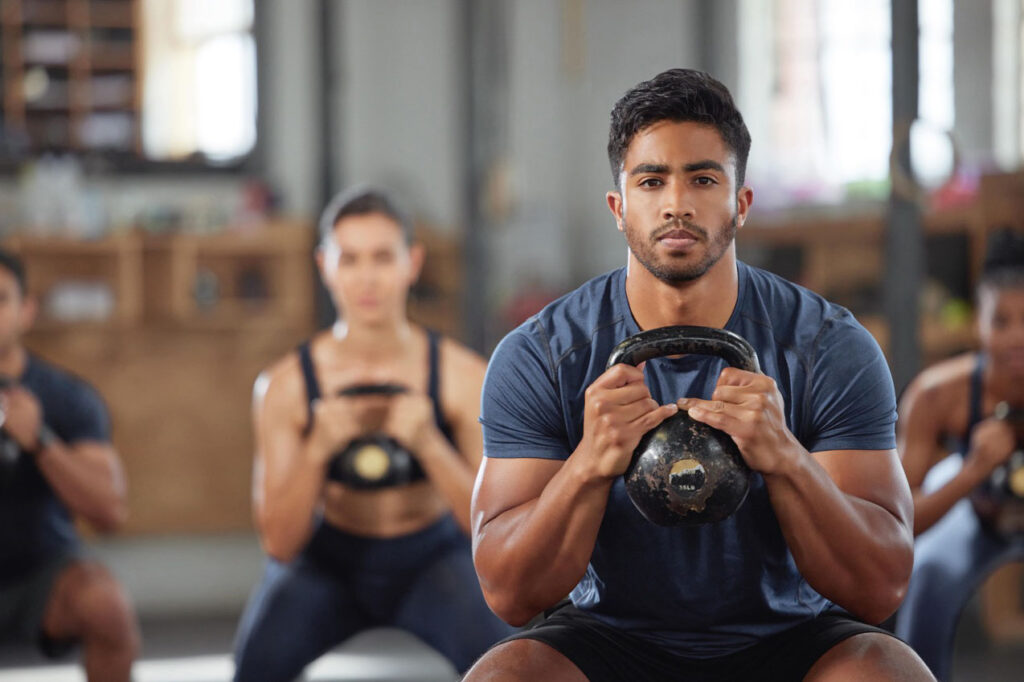Fitness class of people crouched holding kettlebells