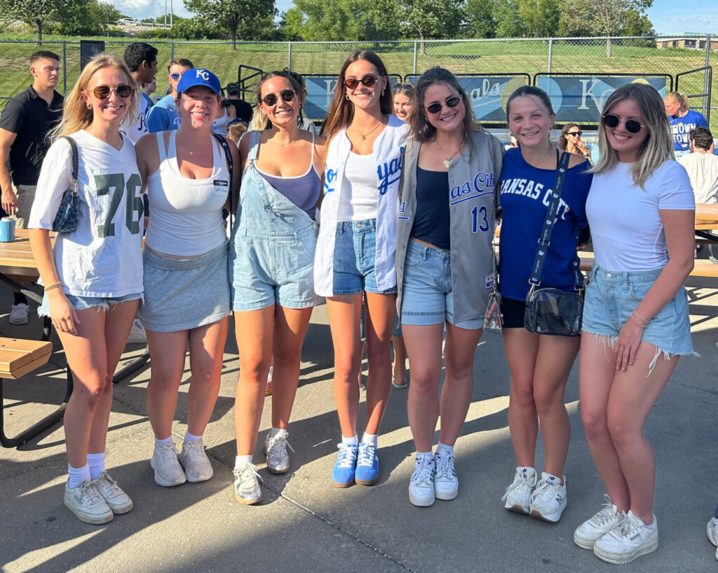 Seven girls in KC Royals attire pose together and Intern Night at the K. 