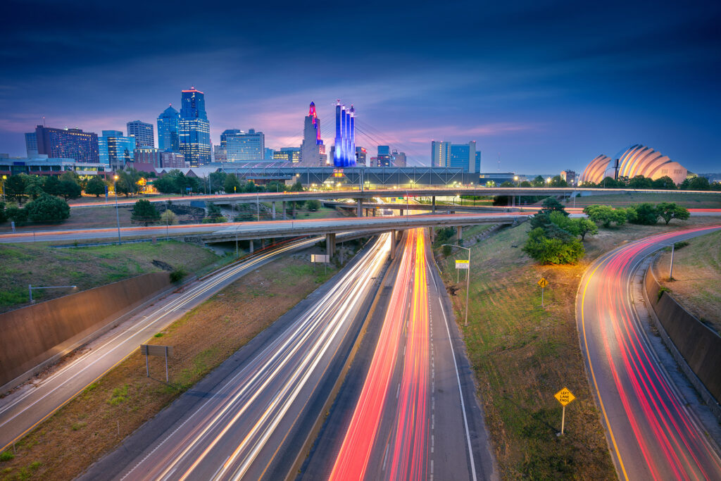 View of downtown Kansas City skyline near nightfall showing highways intersecting and long exposure car lights