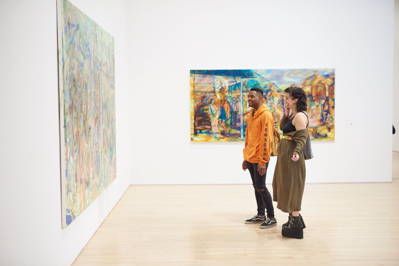 A young couple looking at a large painting in an art museum