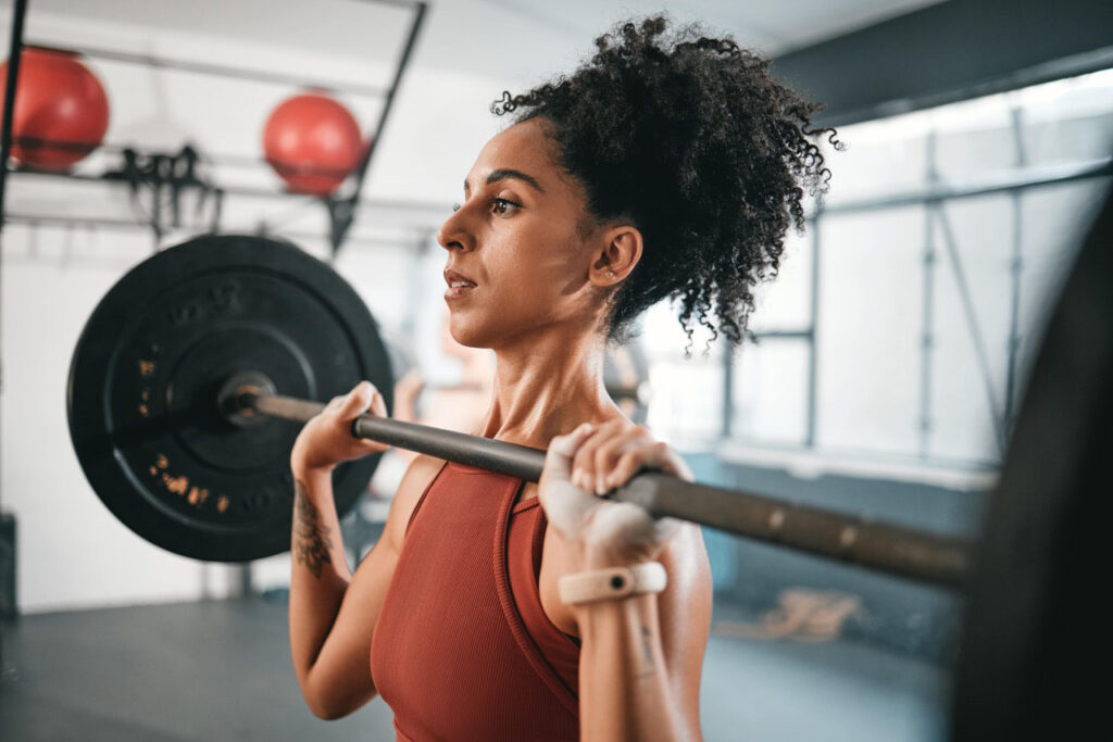 Woman with ponytail holding a barbell at chest level