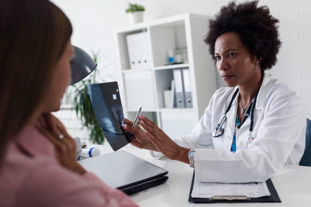 Female doctor speaking with a female patient, showing an xray
