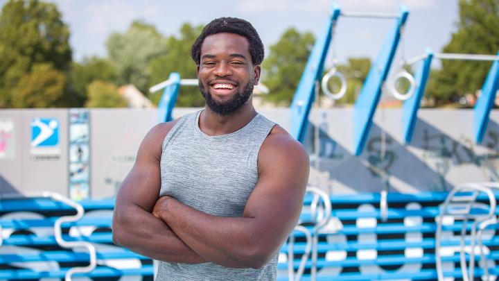 Young man in a sleeveless shirt standing and smiling