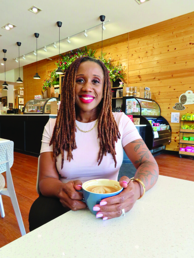 Jenn Miller holding a latte at a coffee shop.
