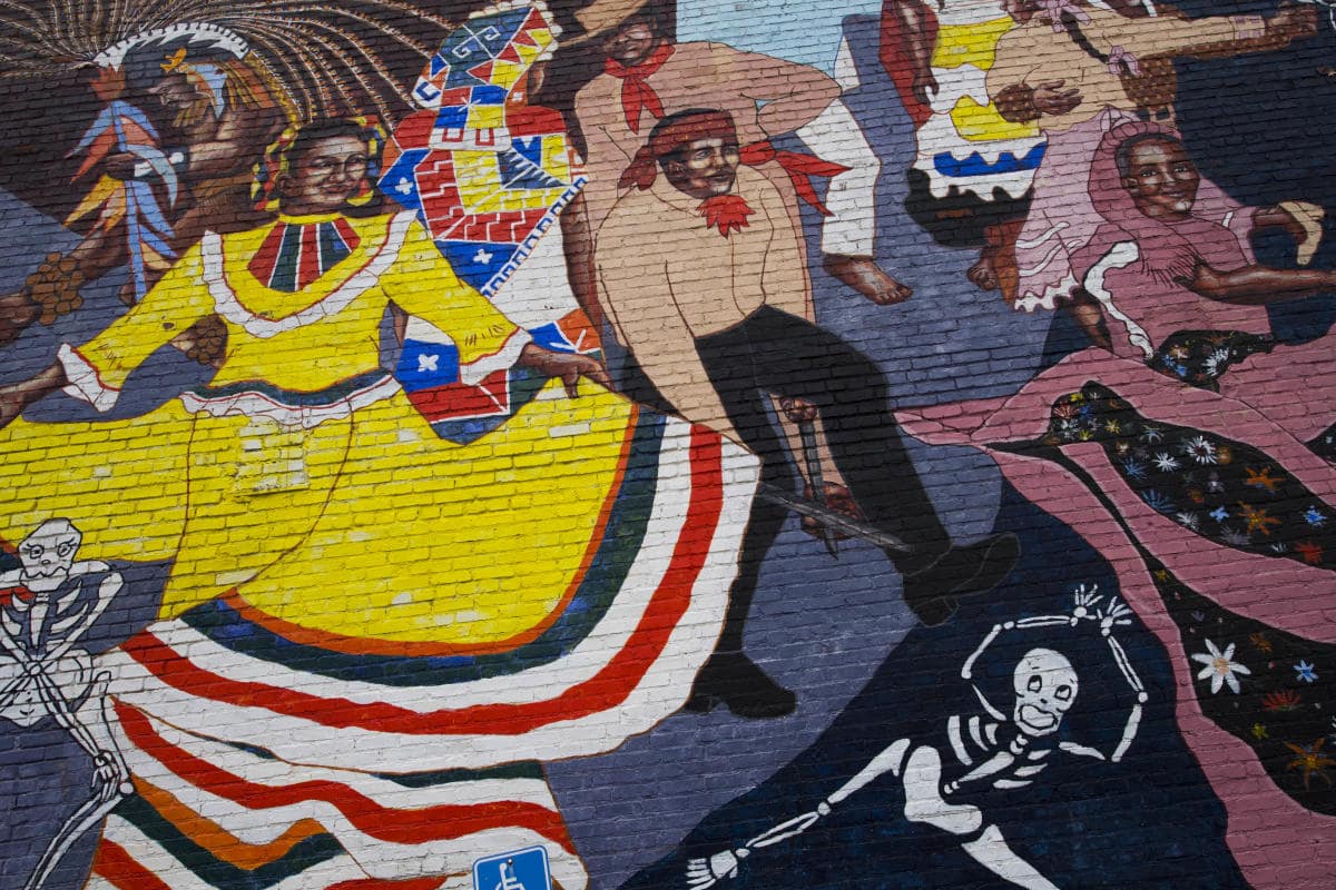 A mural of a dance featuring a woman in a yellow dress with stripes on the hem.