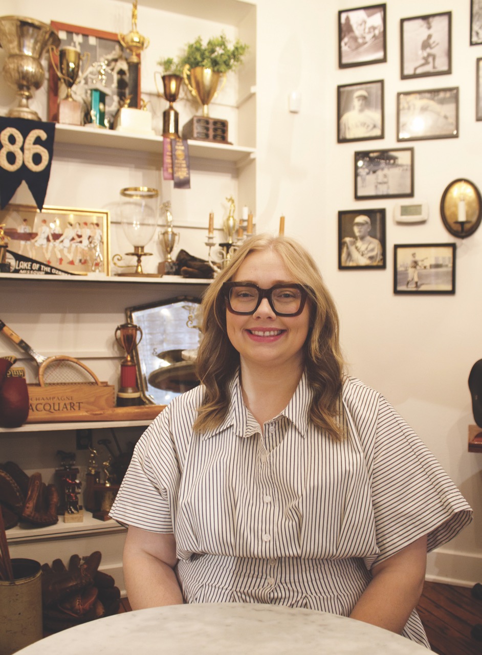 Addie Linn sitting in a room adorned with antique KC sports memorabilia