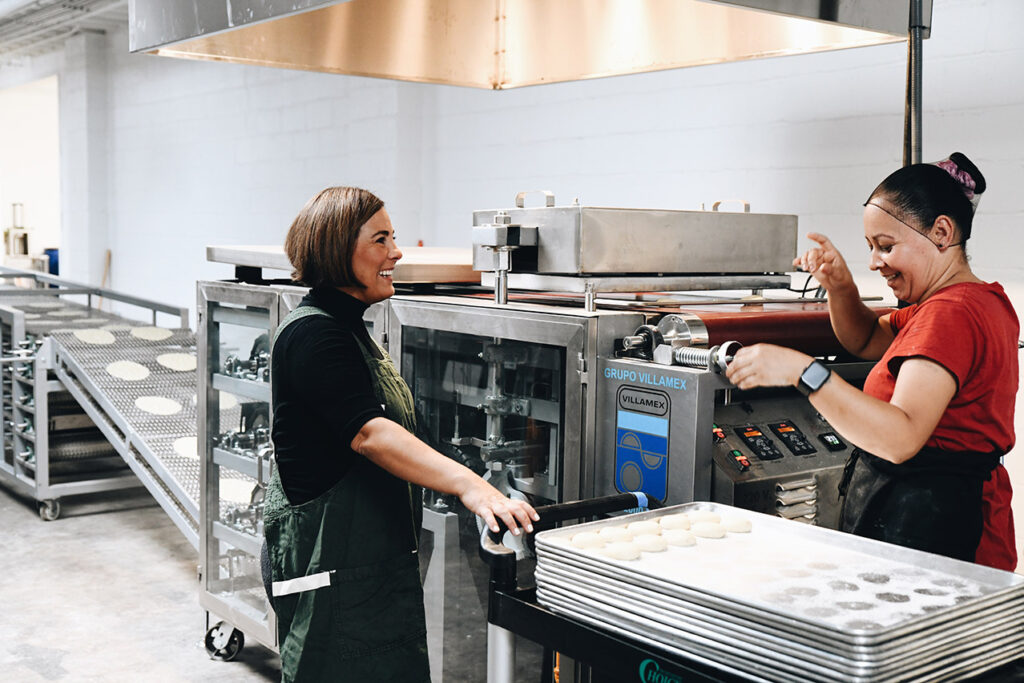 Marissa Gencarelli speaking with an employee making tortillas. 