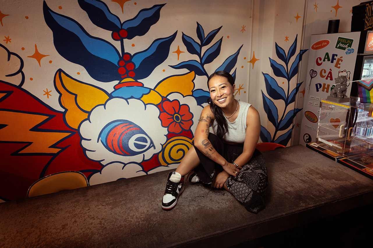 Jackie Nguyen in front of a mural inside Cafe Ca Phe.