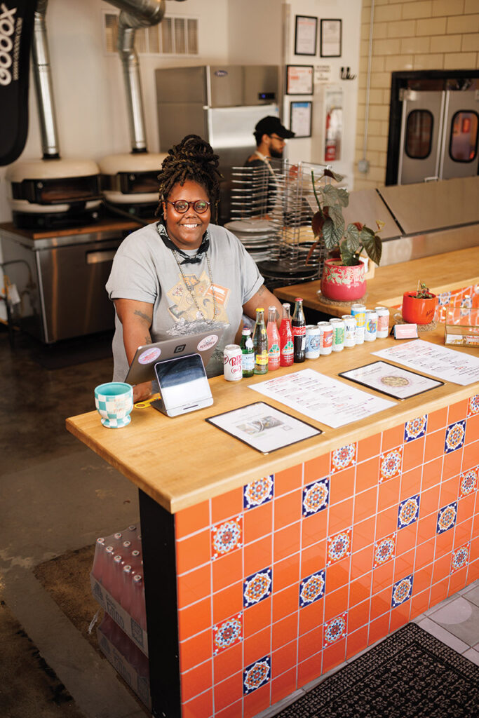 Jhy Coulter standing behind the counter at Orange by Devoured.