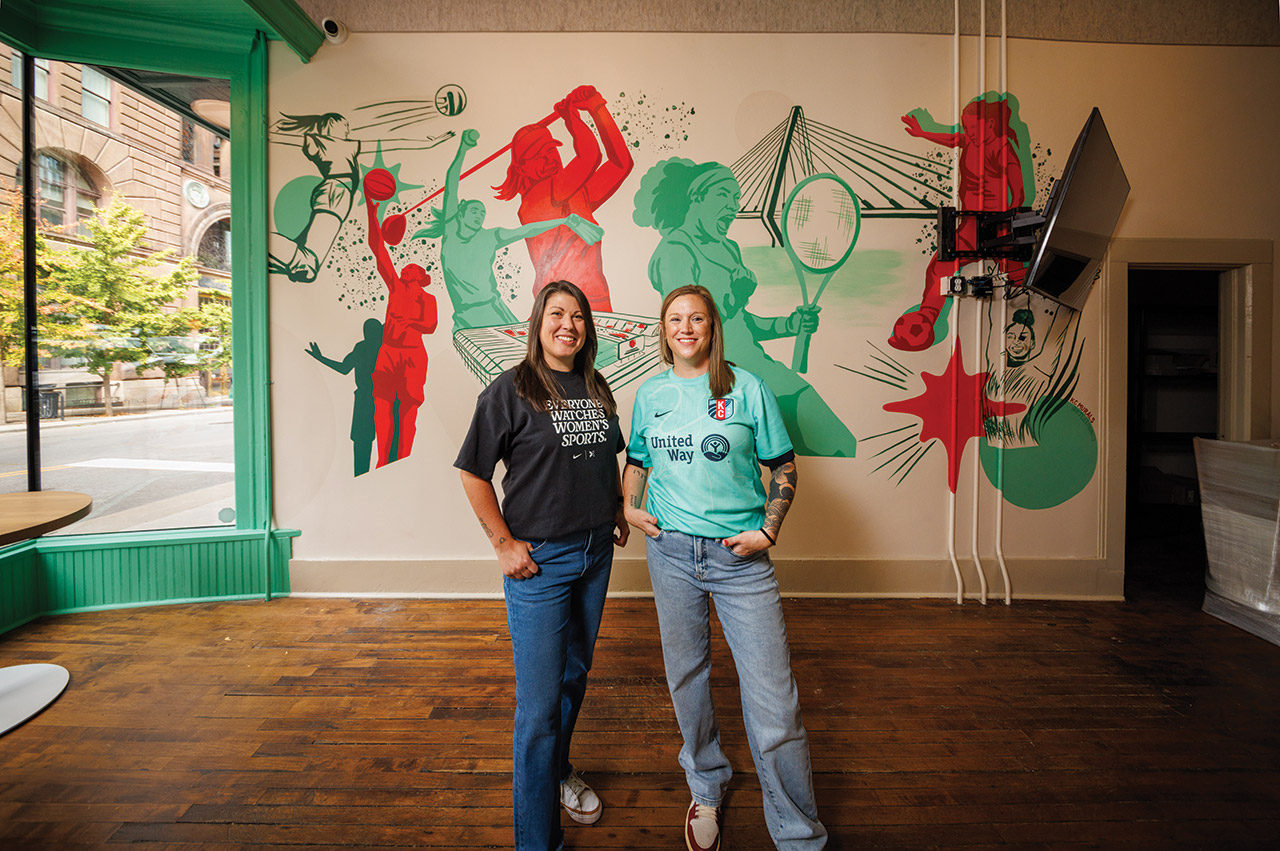 Monica Brady and Rachel Glenn, standing in front of a mural inside The Dub.