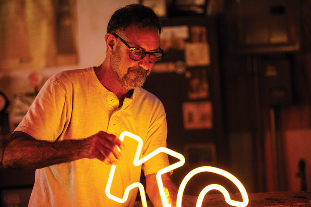 Randy holding a neon "KC" sign.