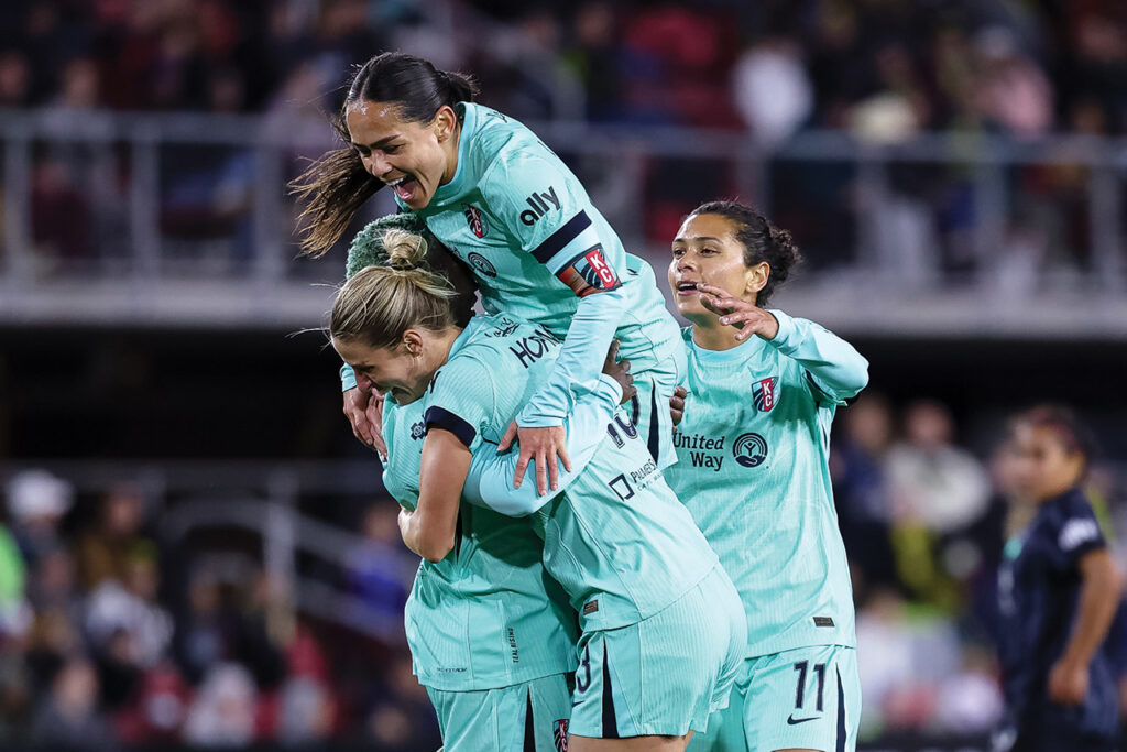 Lo'eau celebrating on the pitch with teammates. 