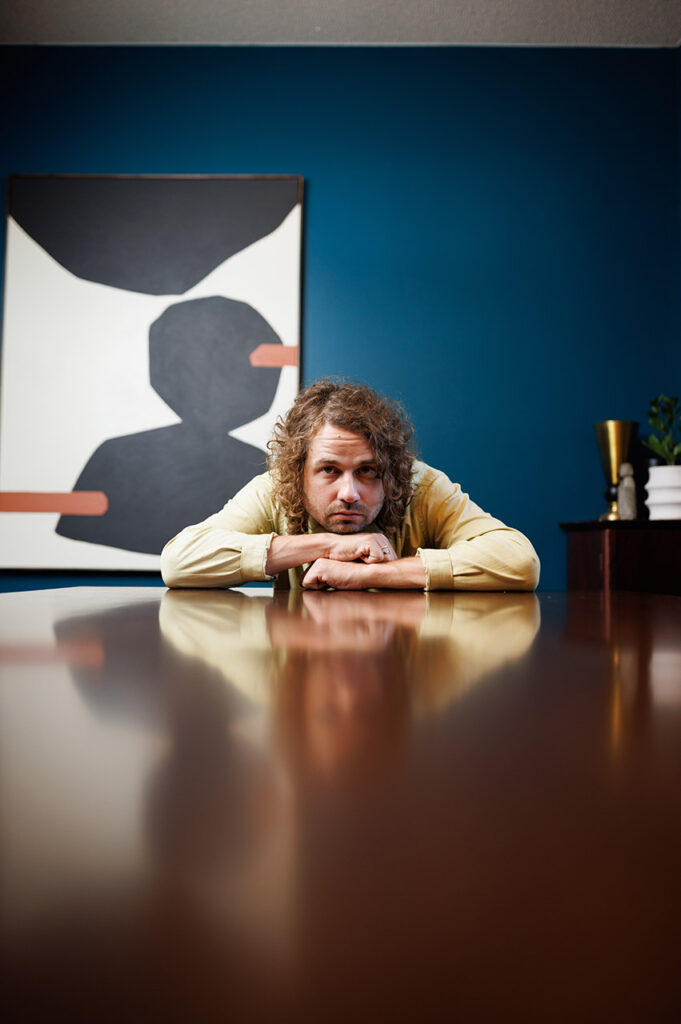 Kevin Morby leaning on a table. 