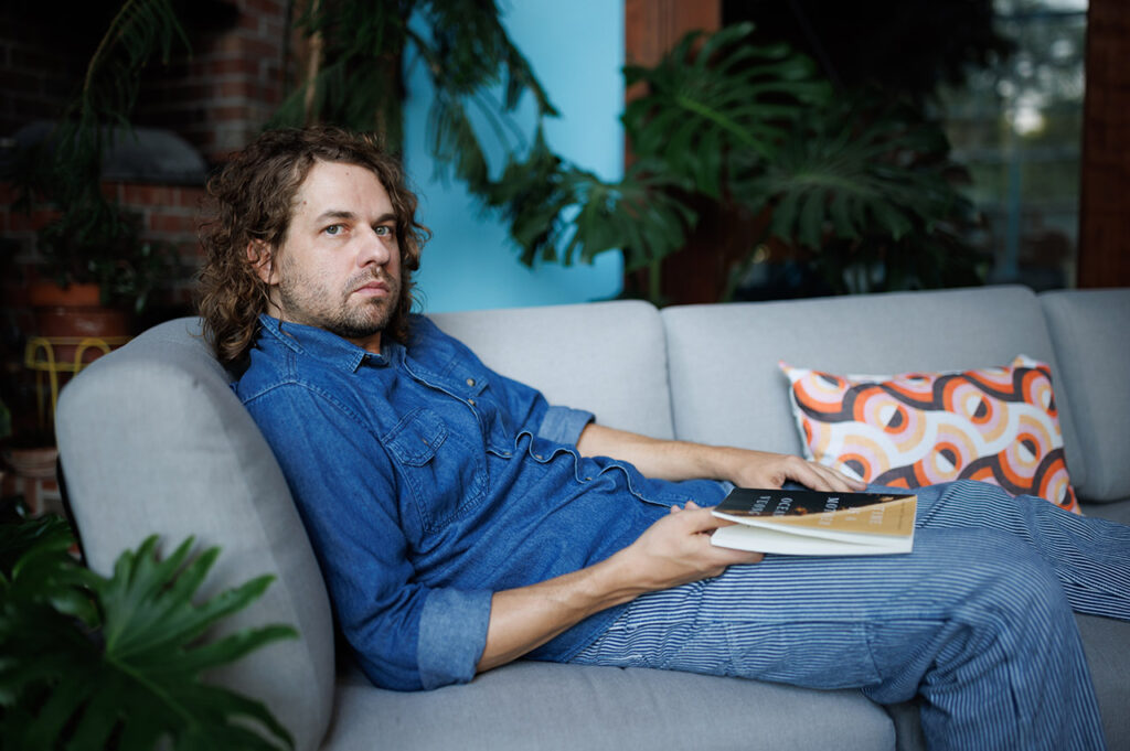 Kevin Morby reading a book on the couch. 