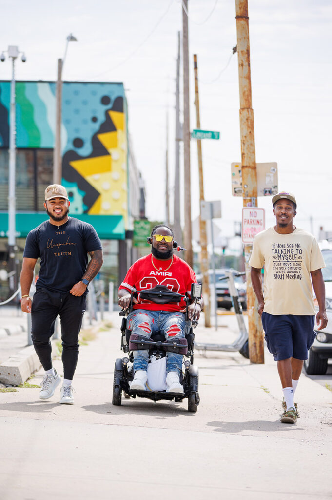 Will Smith strolling down the sidewalk with two friends. 