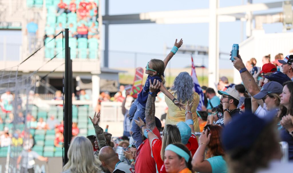 Group of soccer fans holding up a young girl