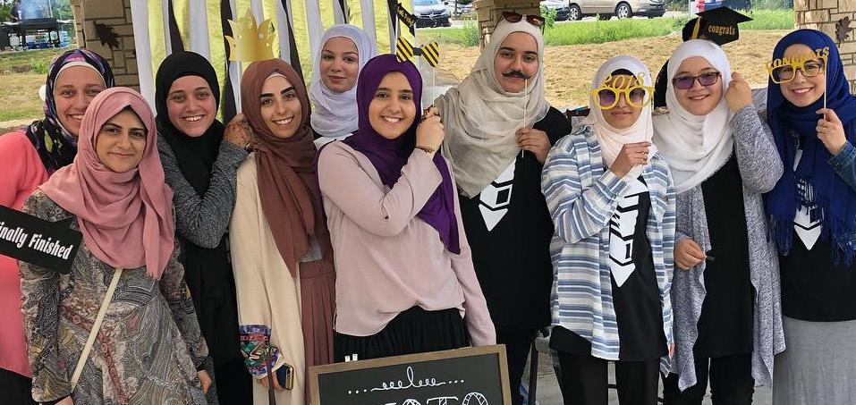 A group of ten women wearing hijabs smile.