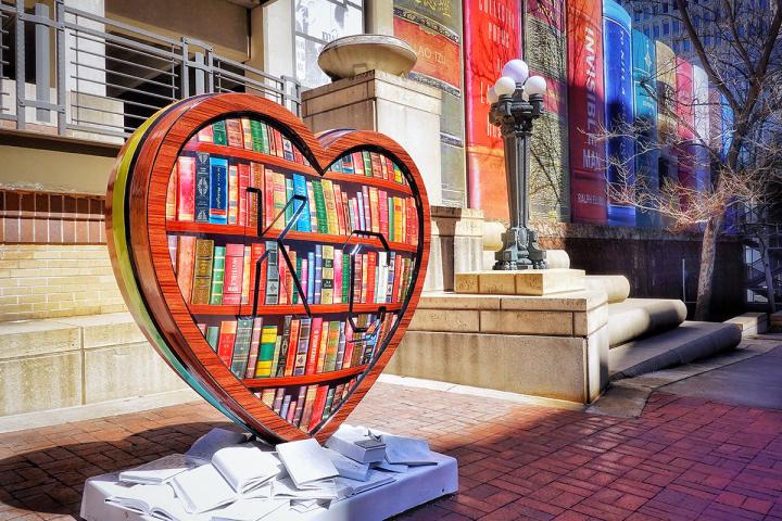 A heart sculpture painted with books, sitting in front of a library