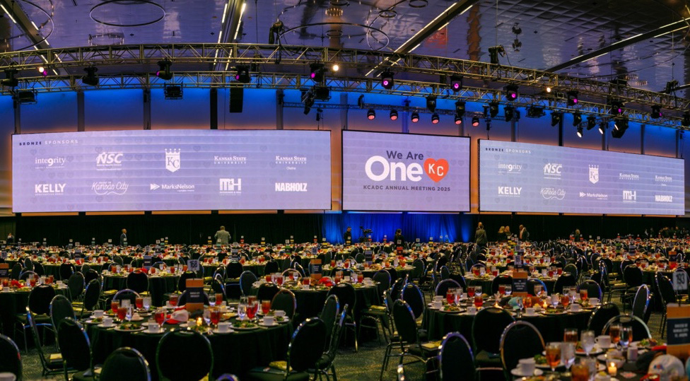 Large room with roundtables and screens displaying the OneKC logo and several company logos