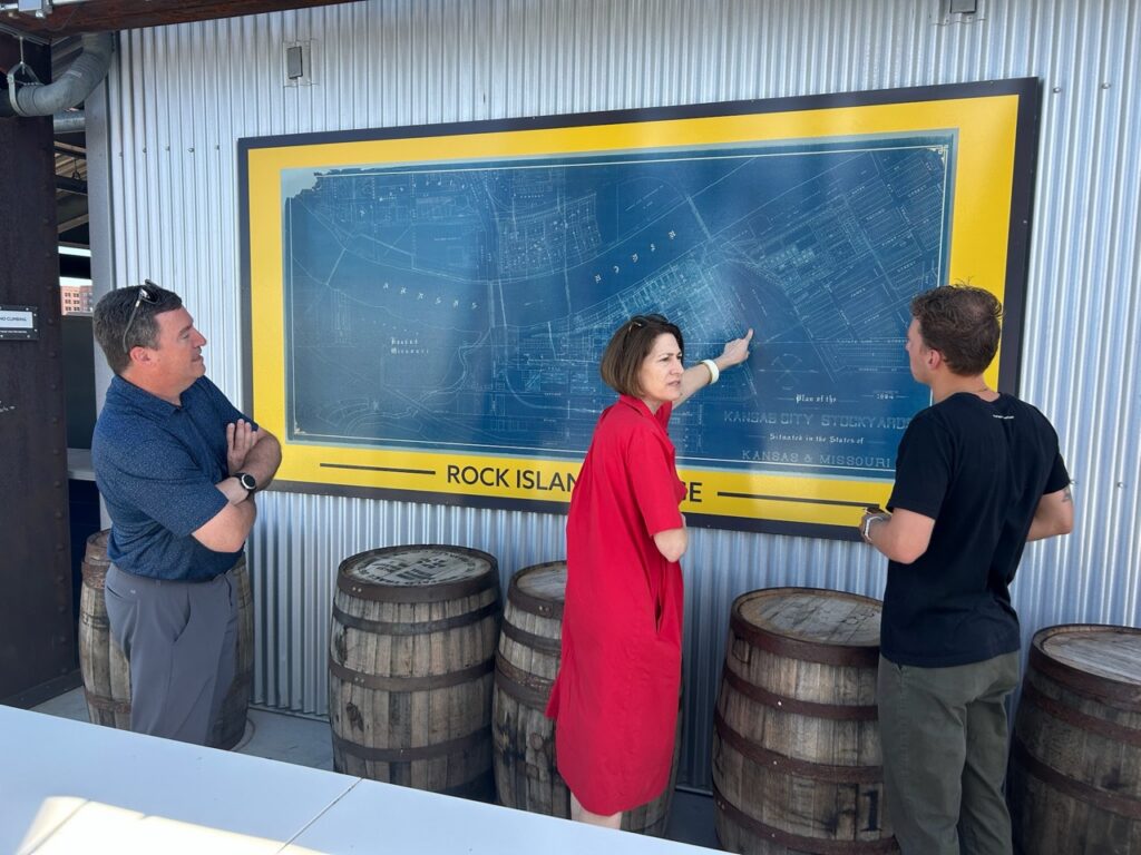 Three people looking at a large vintage schematic of the Kansas River area.
