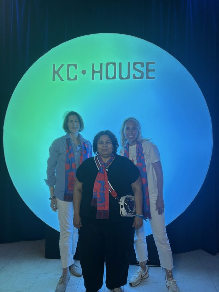 Ashley McDonald and two educators standing in front of a lighted sign reading KC•House