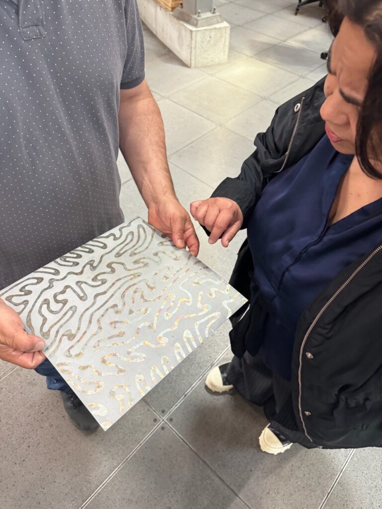 Woman looking at metallic plate with decorative squiggles.