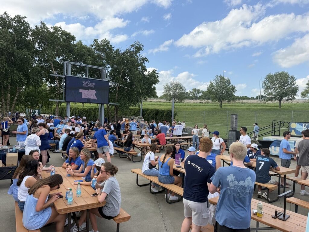 Many interns in an open patio area, seated at picnic tables and playing games